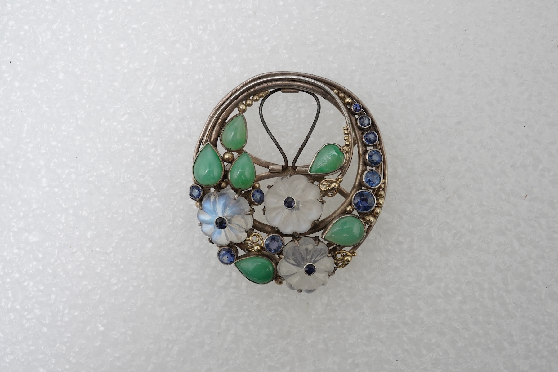 Attributed to Dorrie Nossiter (1893-1977), an Arts & Crafts moonstone, sapphire and jadeite scarf clip, 1920s